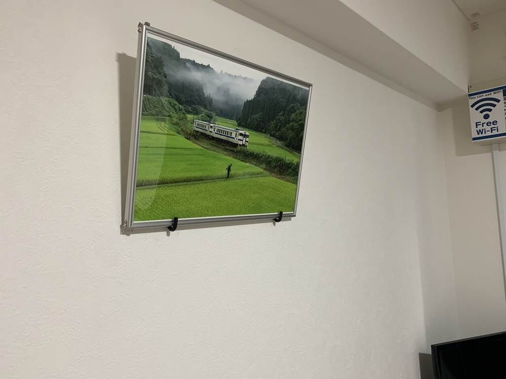 A framed picture of a train on a mountain track with a person standing in the foreground.