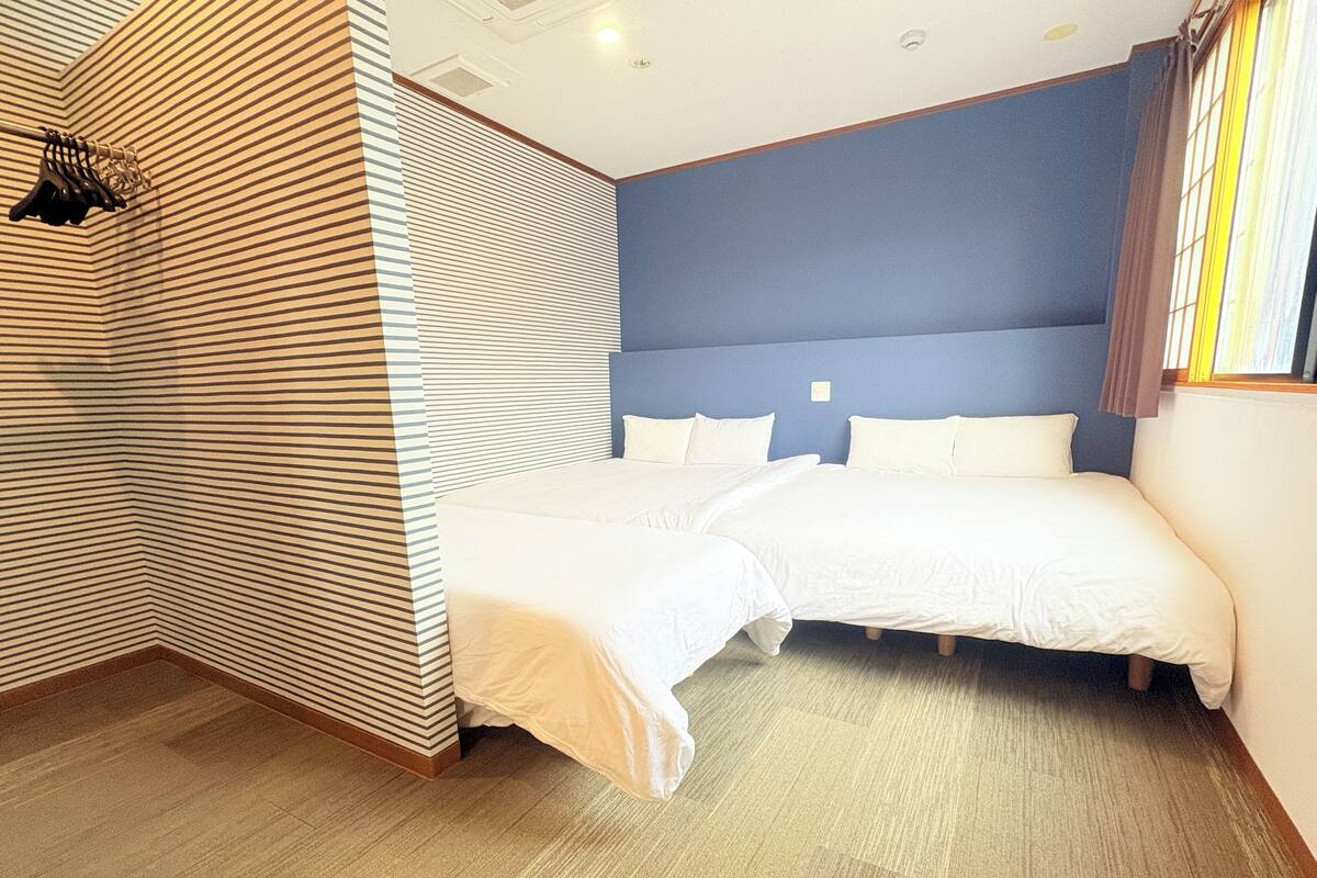 Een hotelkamer met twee enkele bedden, een gestreepte wand en een blauwe accentmuur.