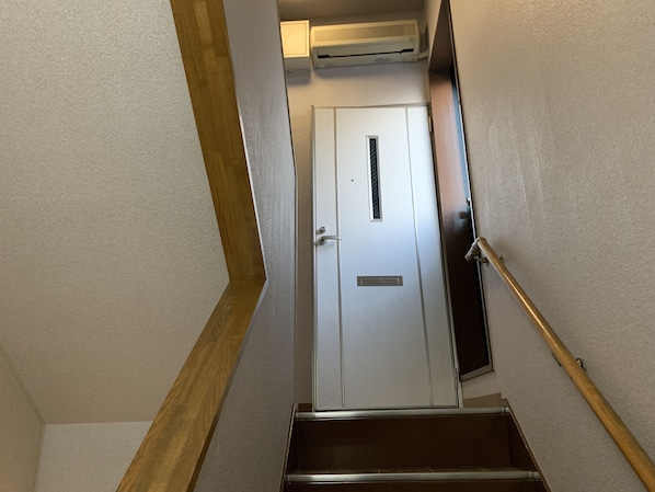 Uma escada leva a uma porta branca, com uma abertura acima.