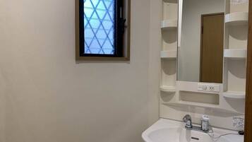 A bathroom with a white sink, a mirror, and a window with a geometric pattern.