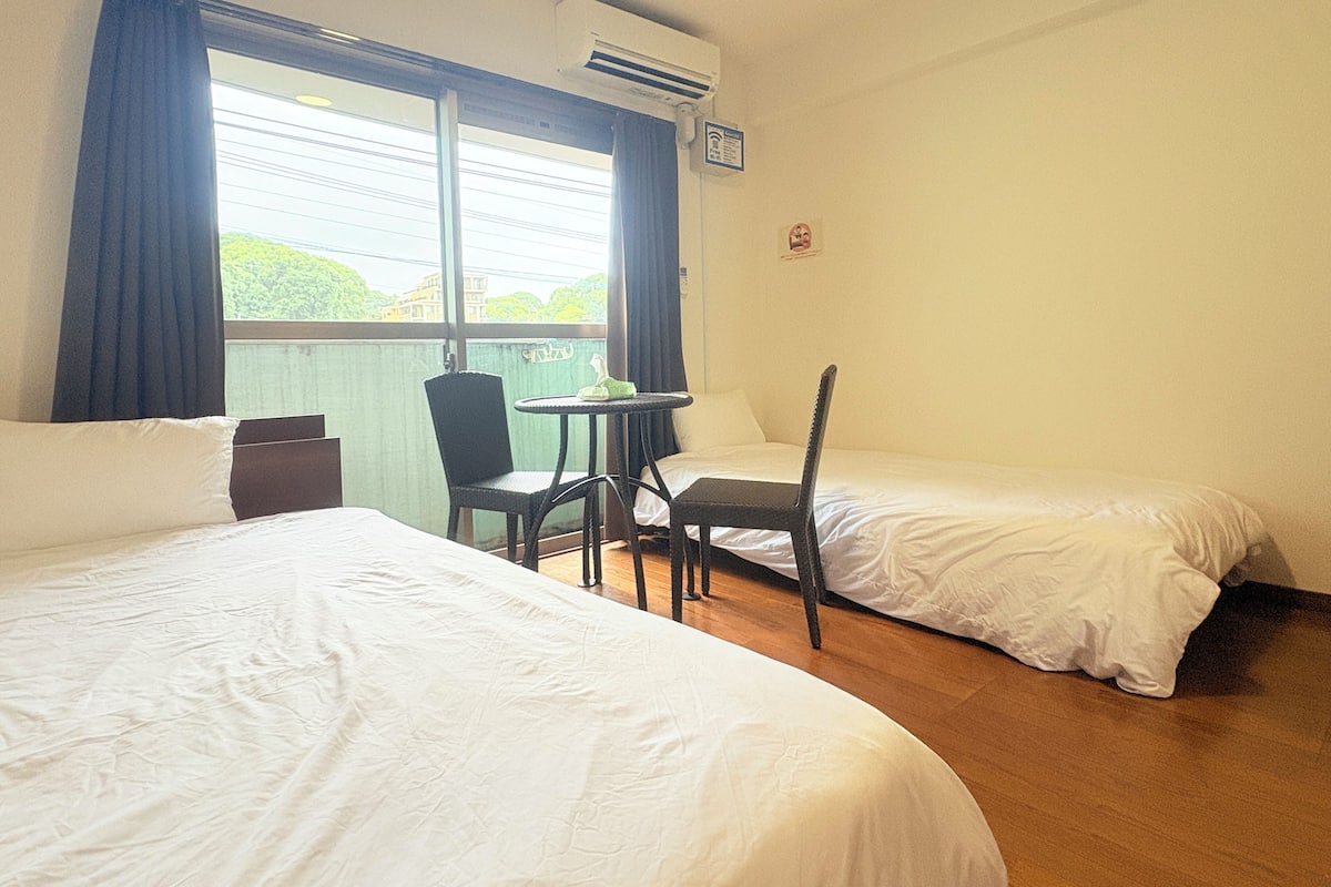 Een hotelkamer met twee enkele bedden, een kleine tafel en stoelen.