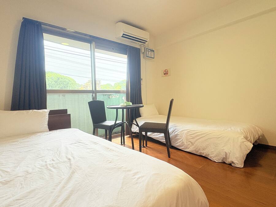 A hotel room with two single beds, a small table, and chairs.