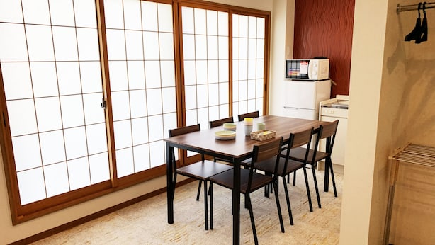 A traditional Japanese-style room with tatami flooring, a wooden dining table with chairs, and sliding shoji doors. - AO-Dazaifu (Chikushino)