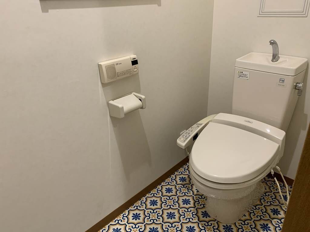 Un bagno piccolo con un water, un porta carta igienica e un lavandino.