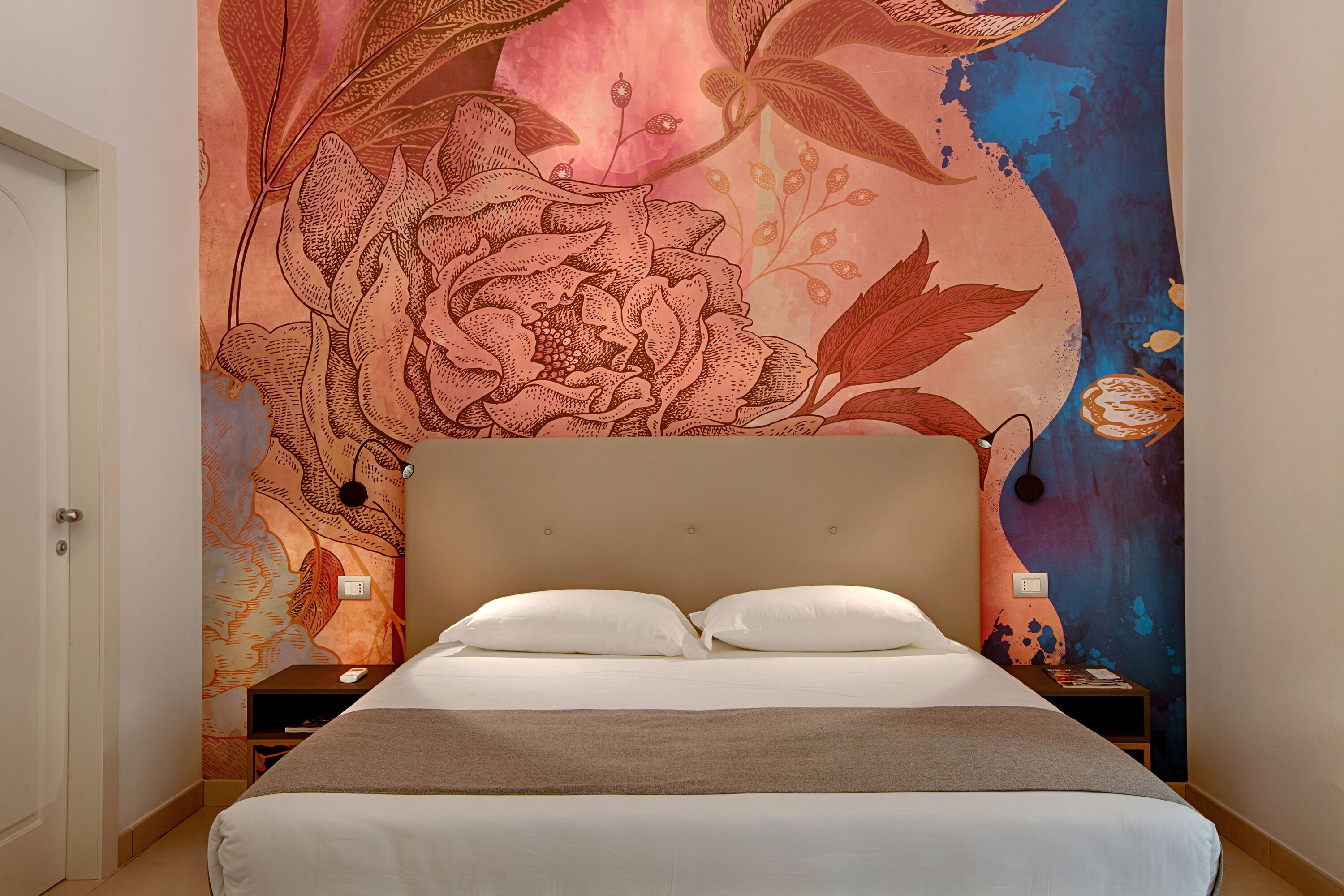 Een slaapkamer met een groot bed, een nachtkastje en een muurschildering.