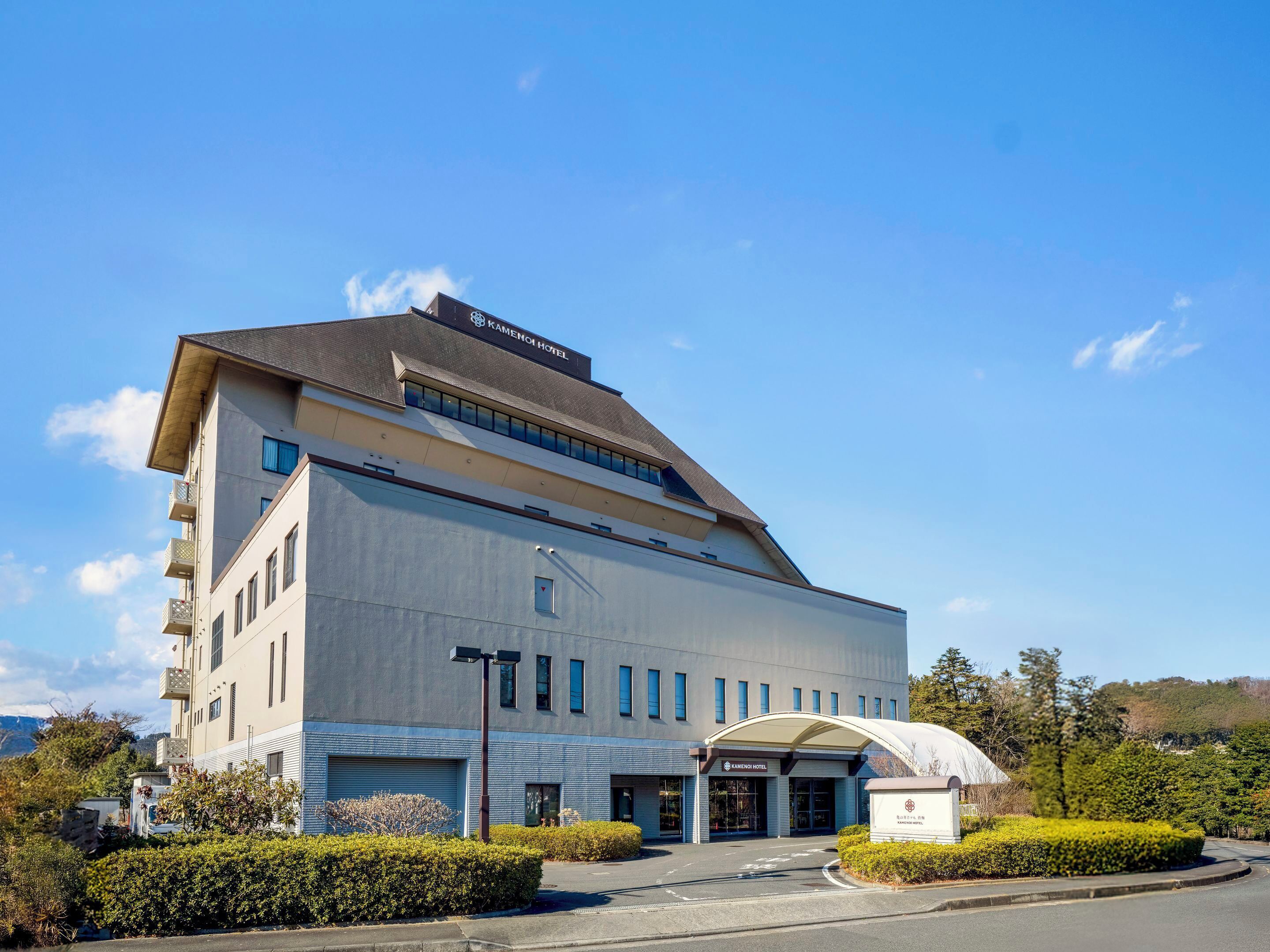 A modern hotel building with a prominent entrance, large windows, and a covered walkway.