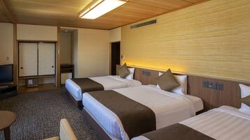 Habitación de hotel con tres camas, televisión, escritorio y piso alfombrado.