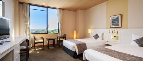 A hotel room with two beds, a desk, a chair, and a TV.