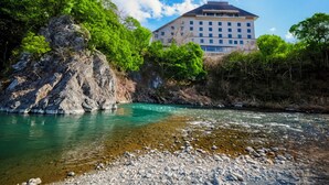Een hotel met een groot gebouw, omringd door weelderige begroeiing en een heldere rivier.