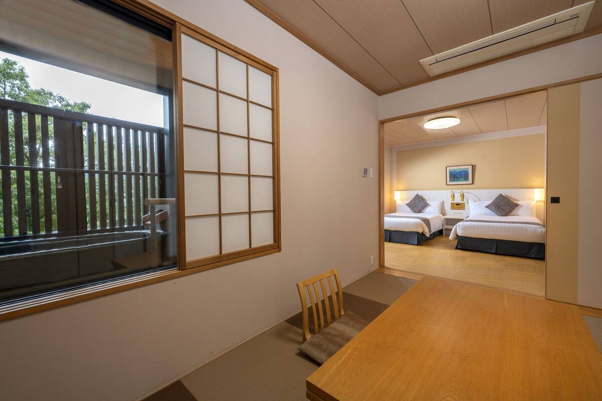 A traditional Japanese room with tatami flooring, a wooden table, and two beds with futons.