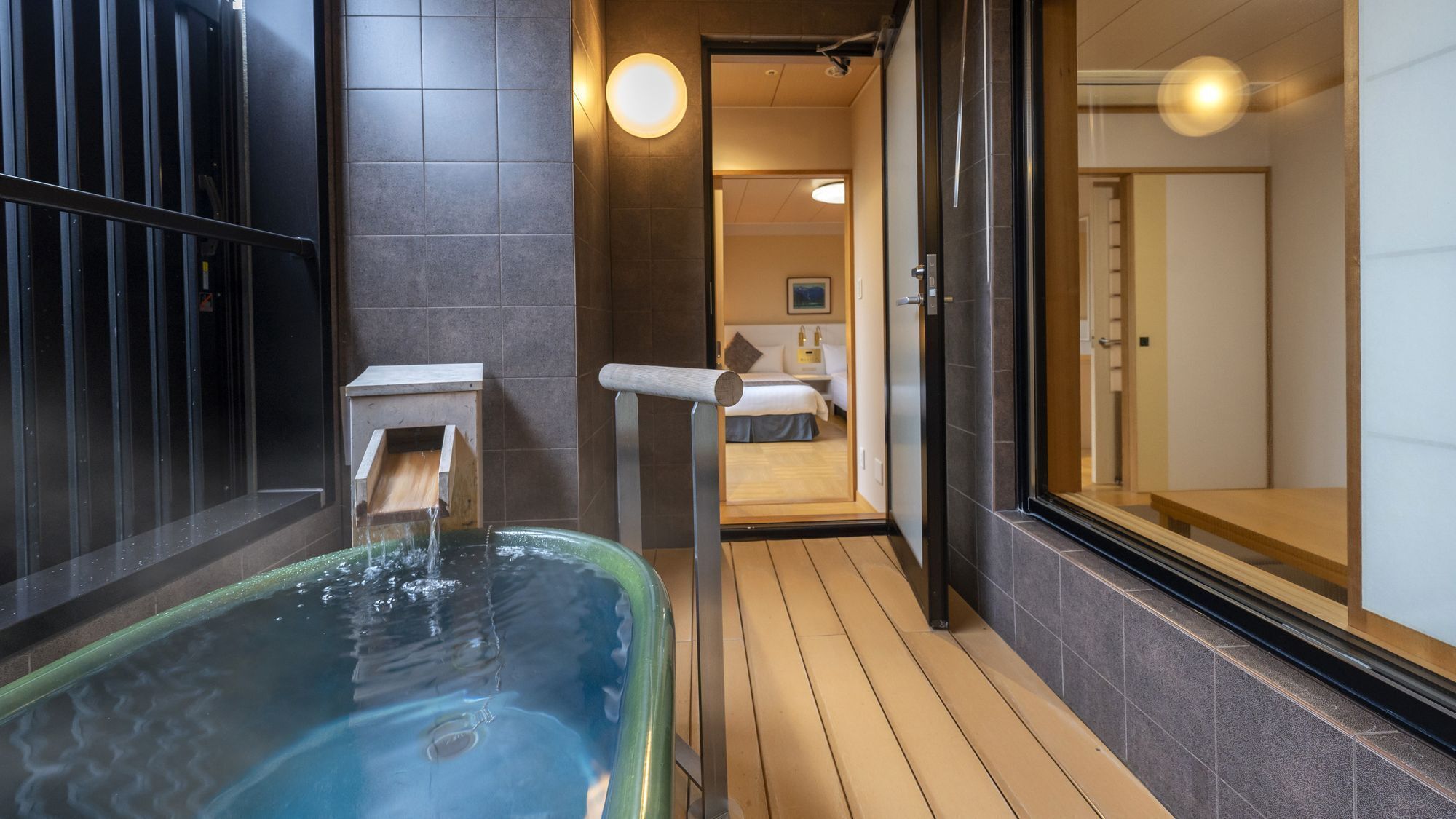A spa area with a hot tub, wooden flooring, and a view into a bedroom.