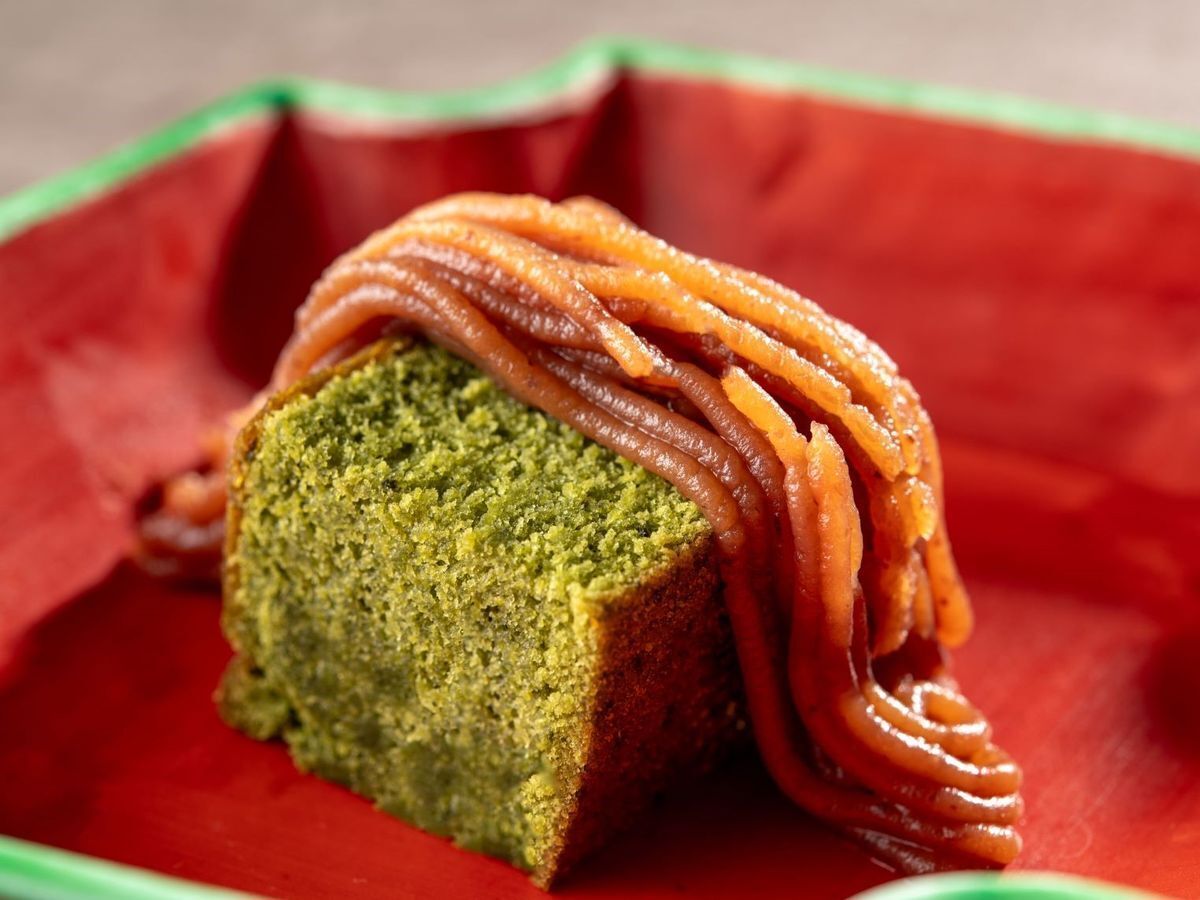 A loaf of green bread with a brown sauce on a red surface.