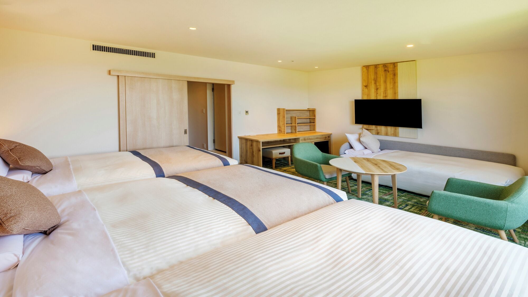 A hotel room with two beds, a desk, a chair, a TV, and a small table.