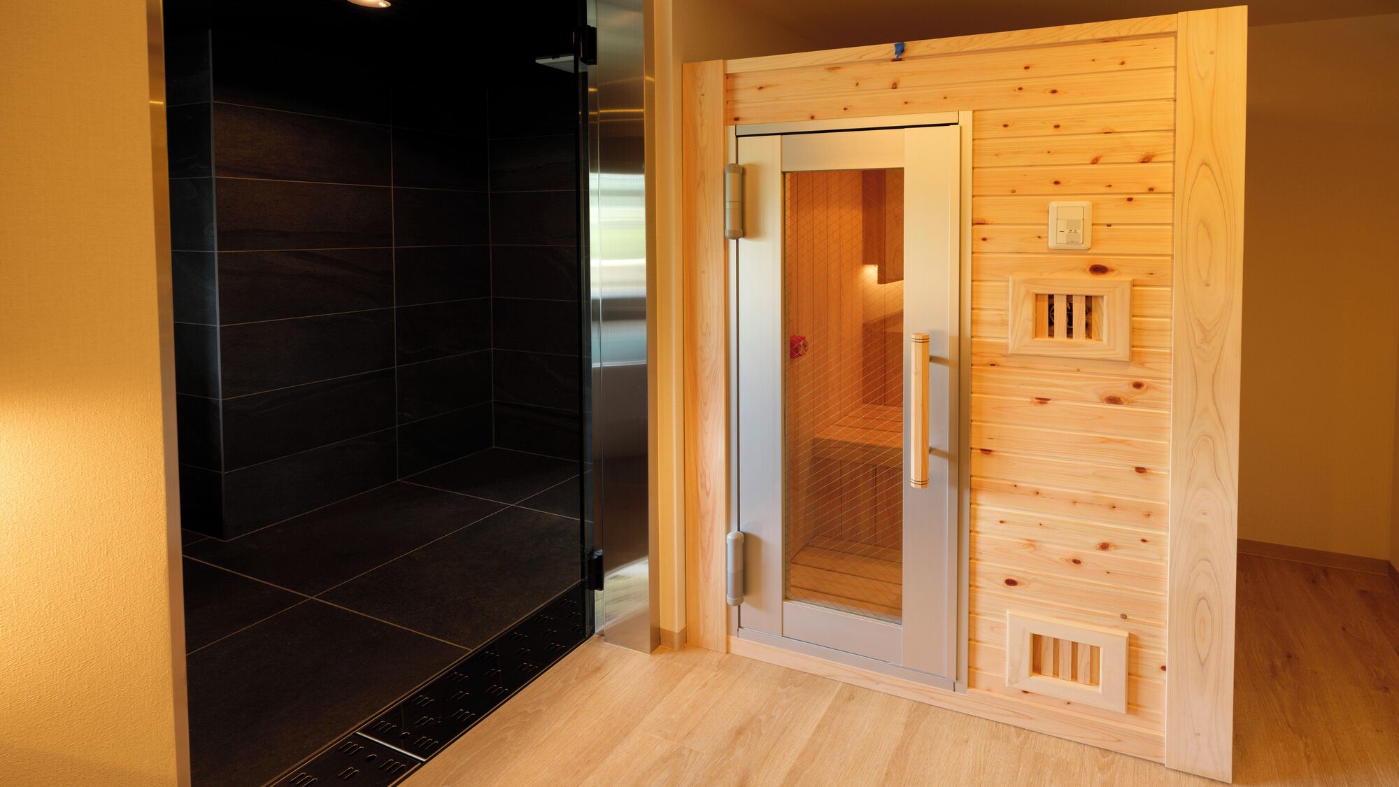 A sauna room with a glass door, wooden paneling, and a tiled floor.