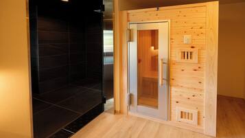 A sauna room with a glass door, wooden paneling, and a tiled floor.