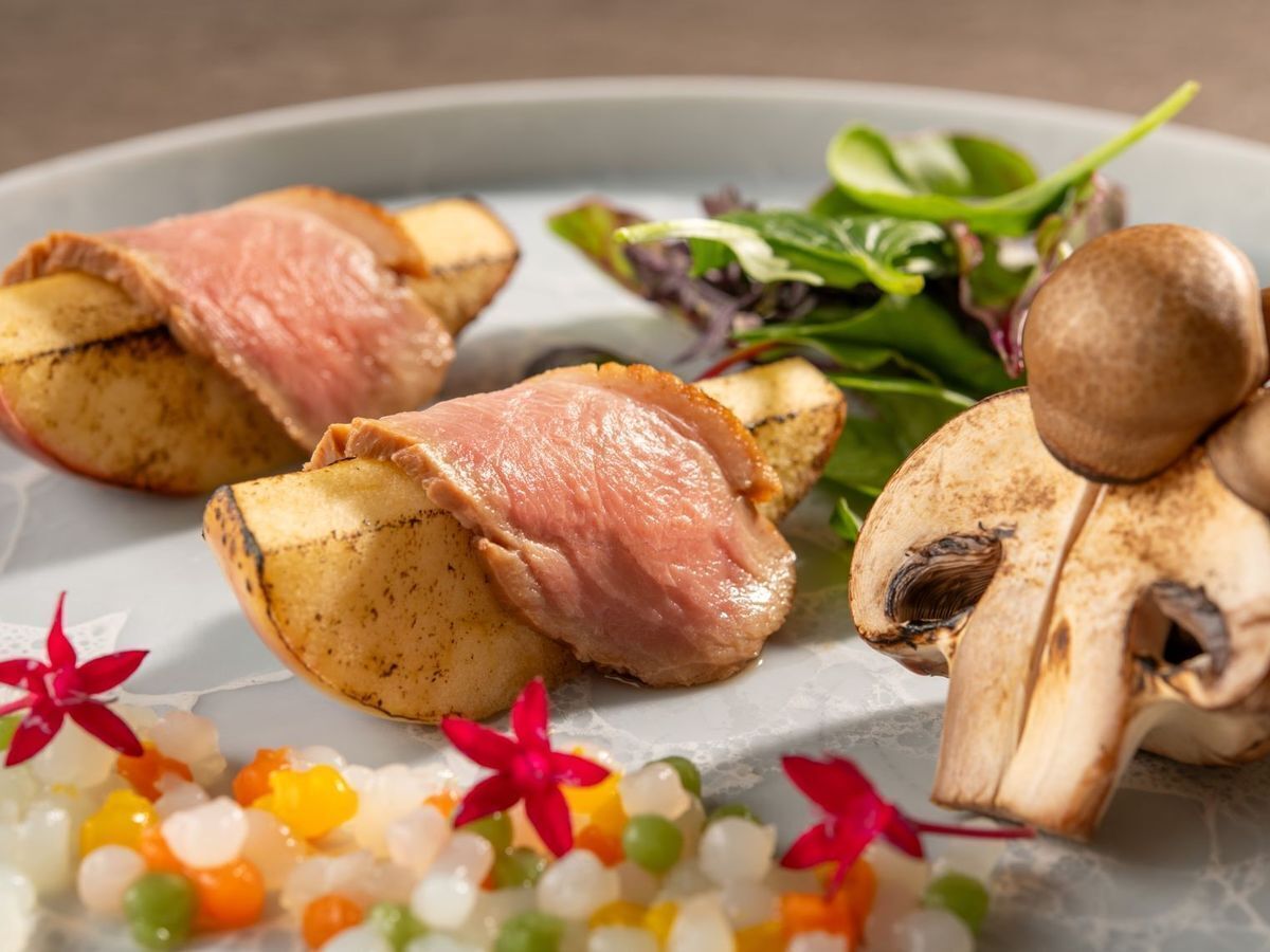 A plate with sliced meat, potatoes, mushrooms, and a salad.