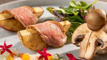 A plate with sliced meat, potatoes, mushrooms, and a salad.