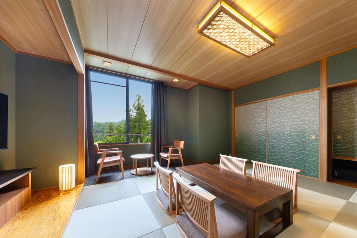 A traditional Japanese-style room with tatami flooring, a wooden dining table, and a view of the outdoors.