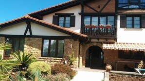 A two-story house with stone walls, large windows, and a balcony with potted plants. - Maddiola Apart 4, Orio (Orio)