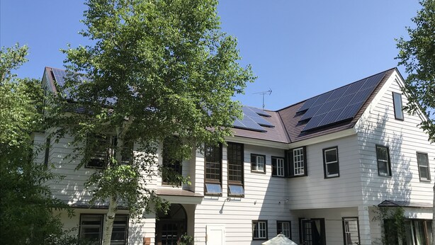 A large, two-story house with a sloped roof, solar panels, and a well-maintained lawn. - Pension Jamoo (Yamanakako)