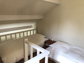 A small, single-bed room with a sloped ceiling and a white railing. - Pension Jamoo (Yamanakako)