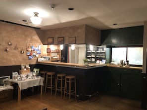 A bar area with stools, a counter, and a display of items on the wall. - Pension Jamoo (Yamanakako)