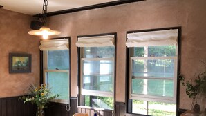 A dining area with a wooden table, chairs, and a vase of flowers. - Pension Jamoo (Yamanakako)