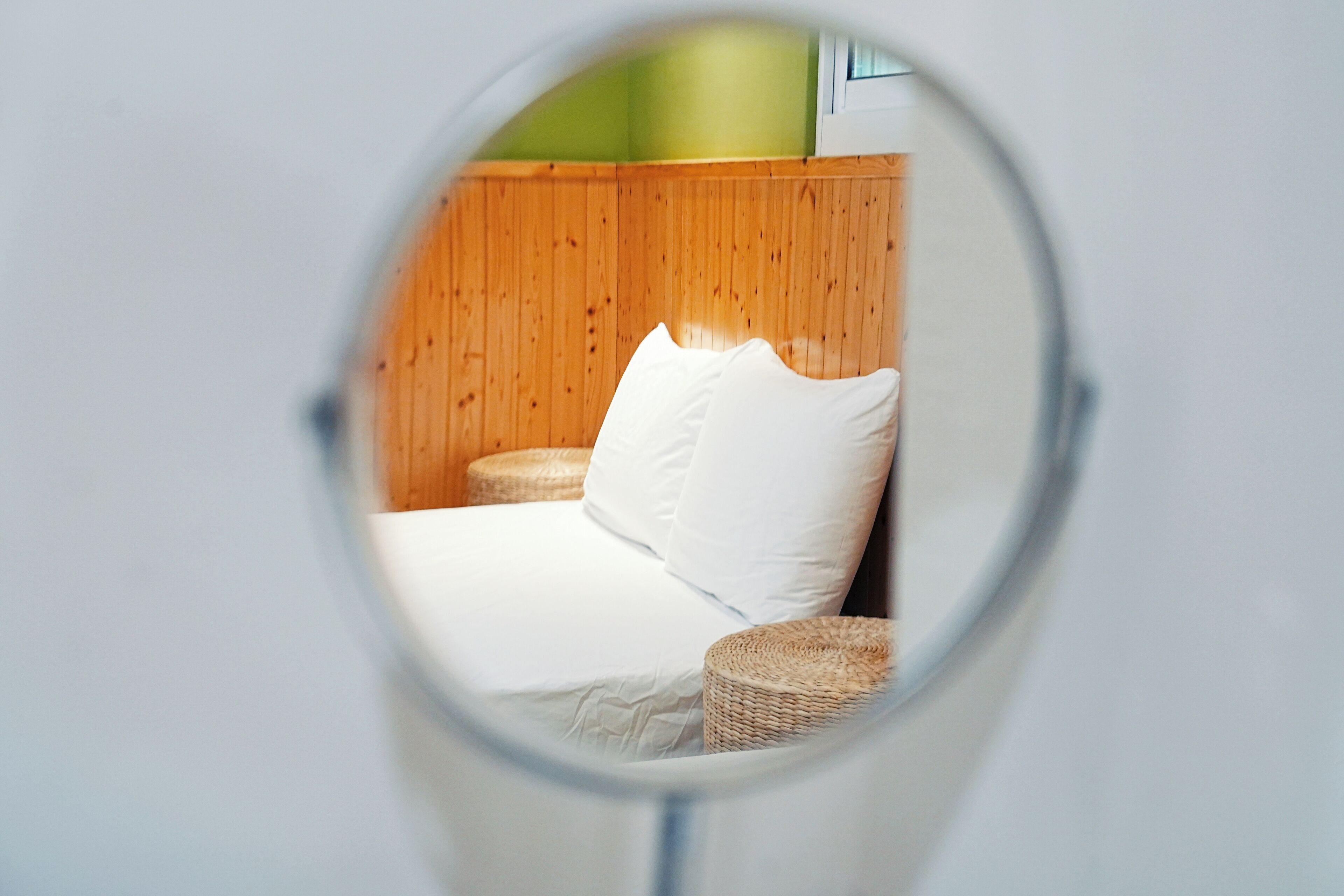 Vista circular de una habitación con una cama, una mesita de mimbre y una pared de madera.