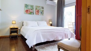 Un dormitorio ordenado con cama, dos lámparas de noche, una mesita de noche y una ventana con cortinas.