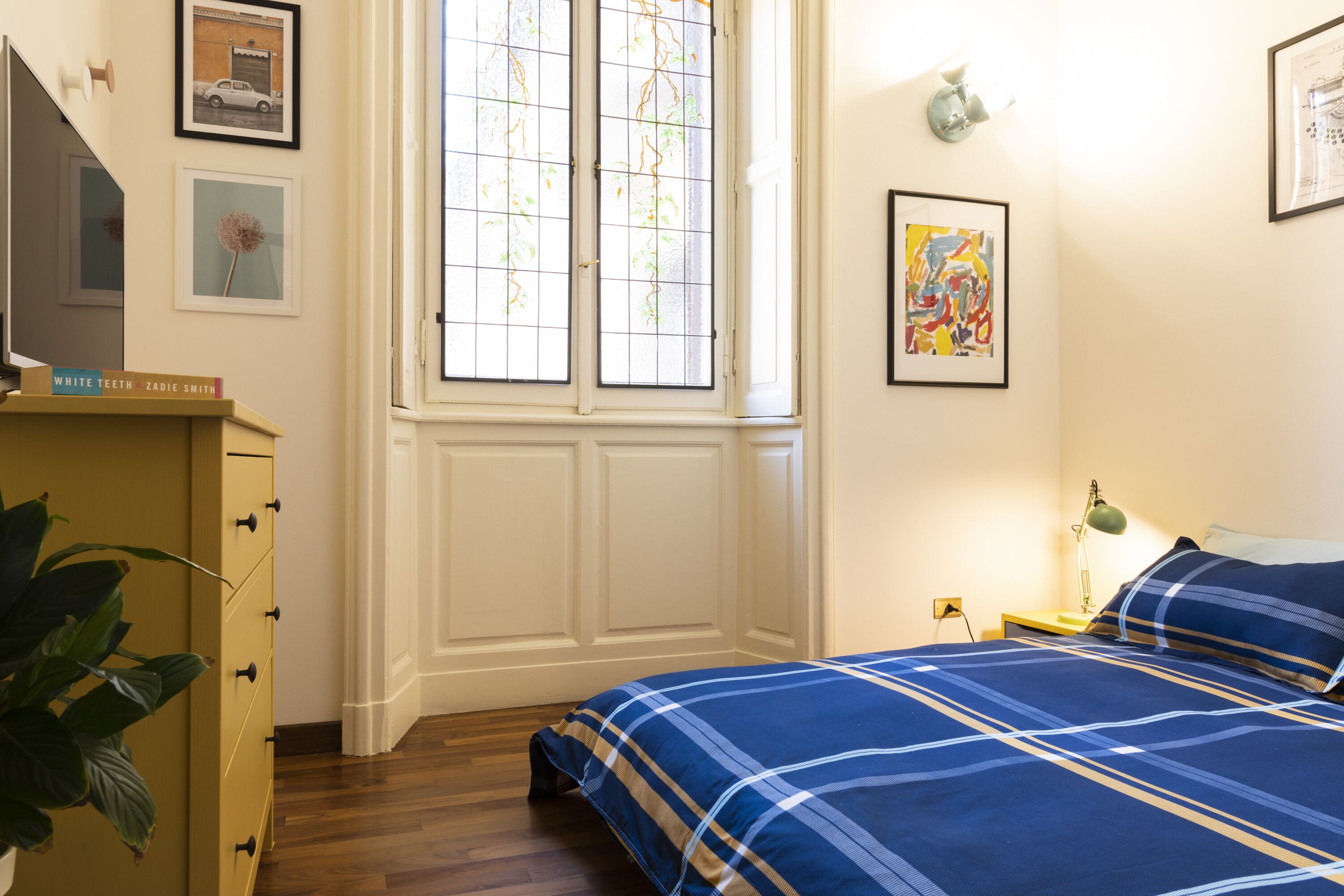 Ein Schlafzimmer mit einem Bett, einem Schminktisch, einem Fenster und Wandbildern.