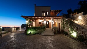 A modern house with a stone facade, a wooden pergola, and a stone staircase leading to the entrance. - Private Villa with Pool & Jacuzzi | Organic Garden | Ideal for Families (RETHYMNO)