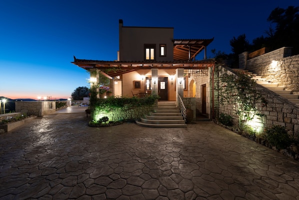 A modern house with a stone facade, a wooden pergola, and a stone staircase leading to the entrance. - Private Villa with Pool & Jacuzzi | Organic Garden | Ideal for Families (RETHYMNO)