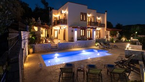 A modern two-story house with a swimming pool, outdoor seating, and stone walls. - Private Villa with Pool & Jacuzzi | Organic Garden | Ideal for Families (RETHYMNO)