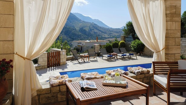 A poolside area with a view of mountains, outdoor seating, and a pergola with curtains. - Private Villa with Pool & Jacuzzi | Organic Garden | Ideal for Families (RETHYMNO)