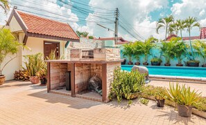A patio area with a barbecue grill, a swimming pool, and various potted plants. - Luxurious 4 bedroom Viewbor Villa - Pattaya Holiday House - Walking Street (Muang Pattaya)