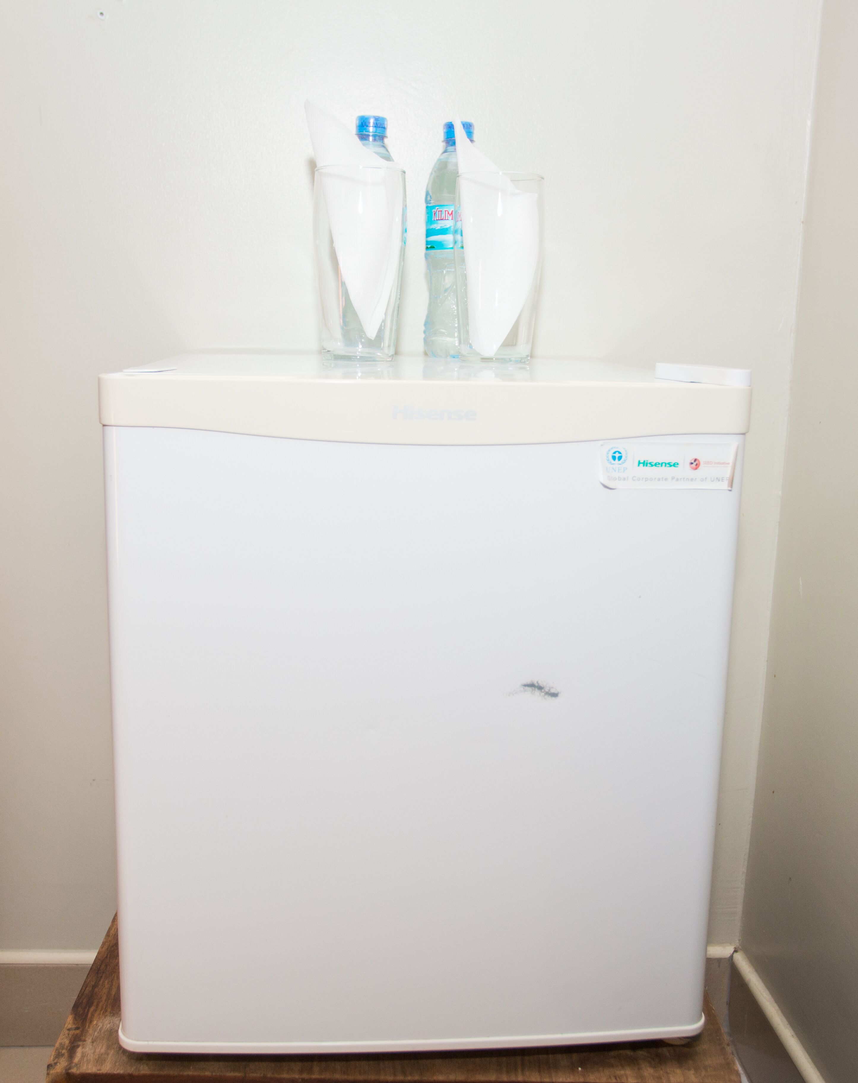 A white Hisense refrigerator with two water bottles on top.