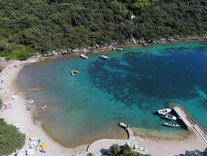 An aerial view of a beach with clear turquoise waters, boats, and a small pier. - Apartment Karla - Two-Bedroom Apartment with Sea View (Korcula)