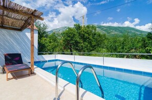 Una piscina con vistas a colinas verdes y un cielo despejado.