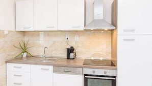 Una cocina moderna con armarios blancos, un lavaplatos de acero inoxidable, una cafetera y un lavavajillas.