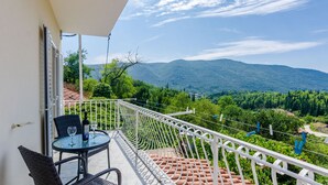 Un balcón con mesa y sillas, con vistas a un paisaje montañoso.