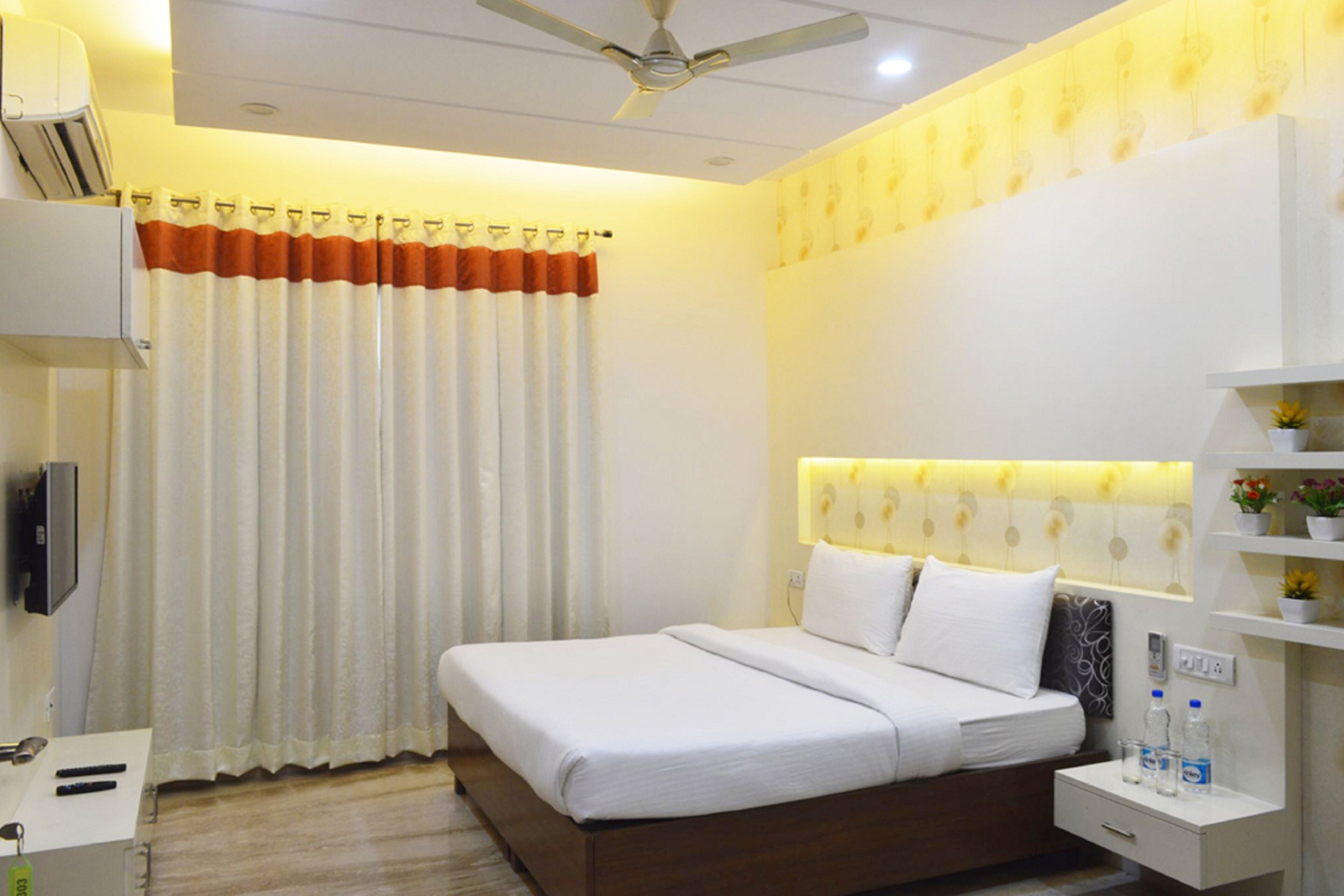 A hotel room with a bed, bedside table, and a wall-mounted TV.