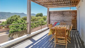 Un área de estar al aire libre con techo, con una mesa y sillas, con vistas a un paisaje pintoresco.