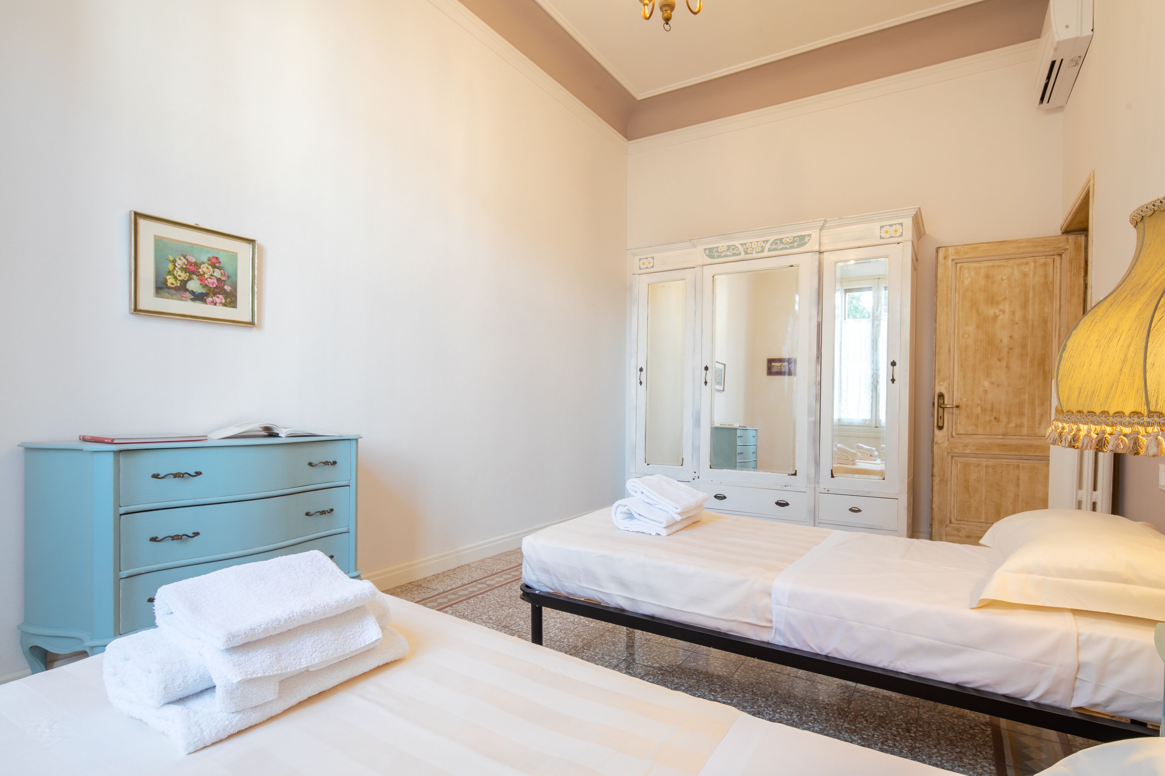 Una camera da letto con due letti, una cassettiera, uno specchio e una lampada.