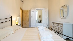 A hotel room with a bed, a nightstand with a lamp, a wardrobe, and a dresser. - Santa Maria Novella 4 Bedrooms by Mmega (Florence)