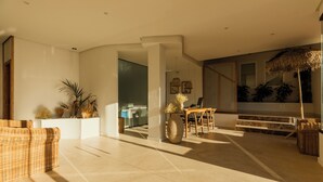 A spacious living area with a large window, a dining table, and a seating area with wicker furniture. - Paya II / 2 (Formentera)