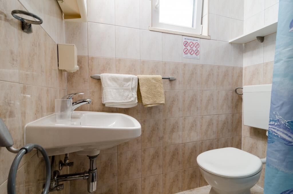 Une salle de bain avec un lavabo, deux serviettes, des toilettes et une fenêtre.