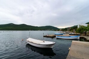 A calm lake with boats docked at a pier, surrounded by hills and a small town.