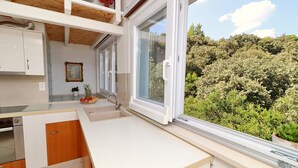 A modern kitchen with white cabinets, a wooden countertop, and a large window overlooking a garden. - Apartments Villa Cebalo Kor (Korcula)
