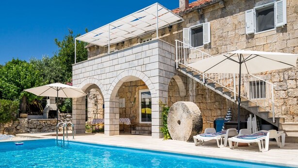 Ein Steinhaus mit Swimmingpool, Außenbereich und einer Treppe.