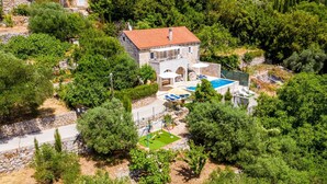 Ein Steinhaus mit rotem Ziegeldach, einem Schwimmbad und einem Garten.